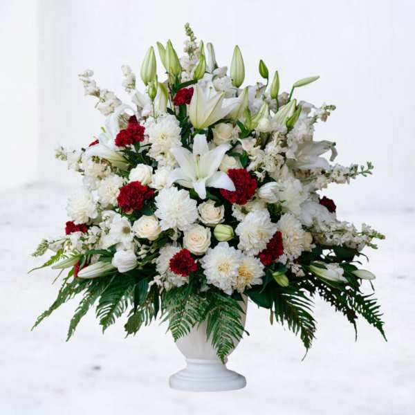 White and red floral arrangement in a white pedestal vase