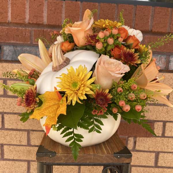 Fall floral arrangement in a white pumpkin container with roses and mums