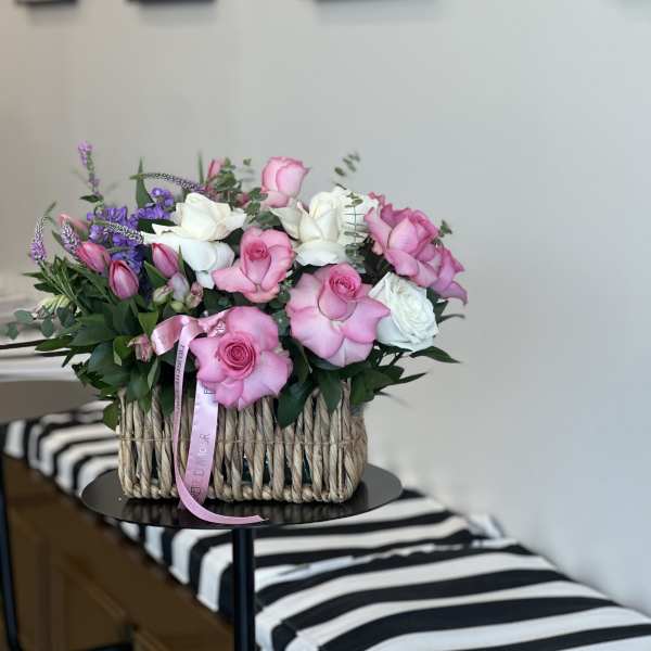 Pink and white roses arranged in a woven basket