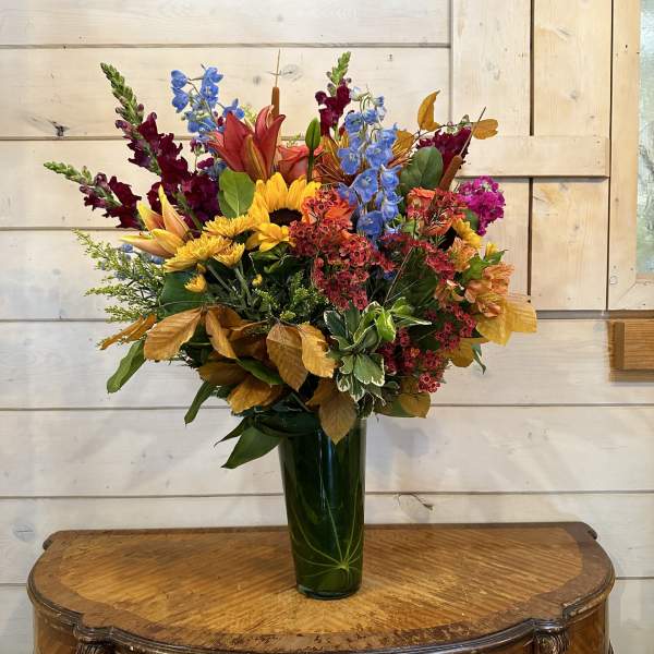 Colorful mixed bouquet in a tall green glass vase