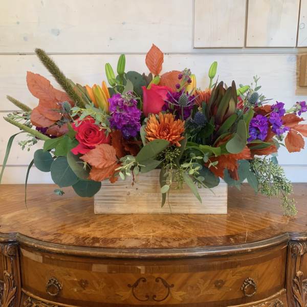 Autumn floral arrangement in a wooden box with roses, lilies, and purple blooms