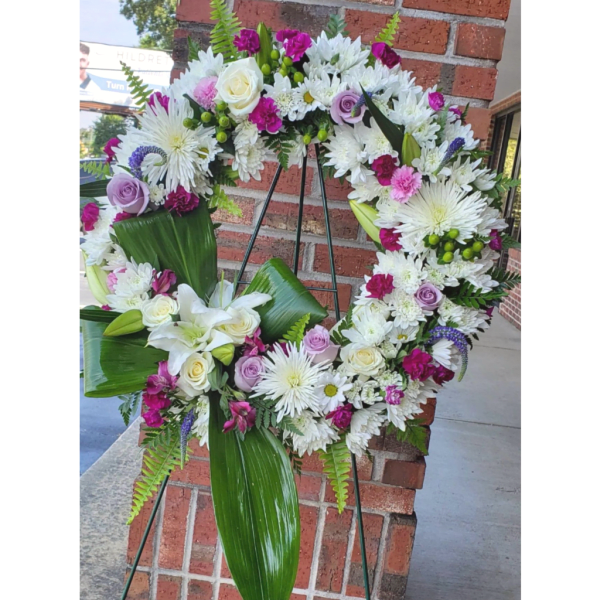 Circular floral wreath on a stand with white, pink, and lavender flowers