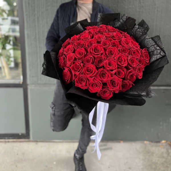 Large bouquet of red roses wrapped in black paper with white ribbon