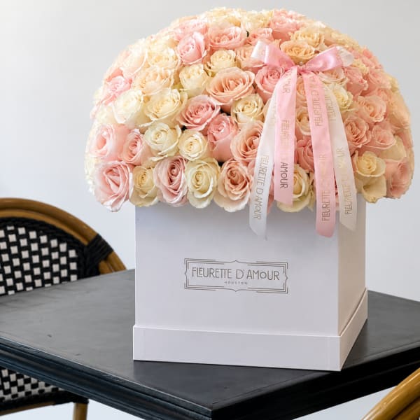 Large box arrangement of pink and cream roses with ribbon