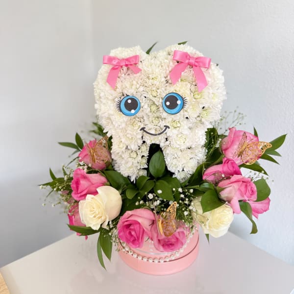 Heart-shaped white flower arrangement with pink bows and roses in a pink box