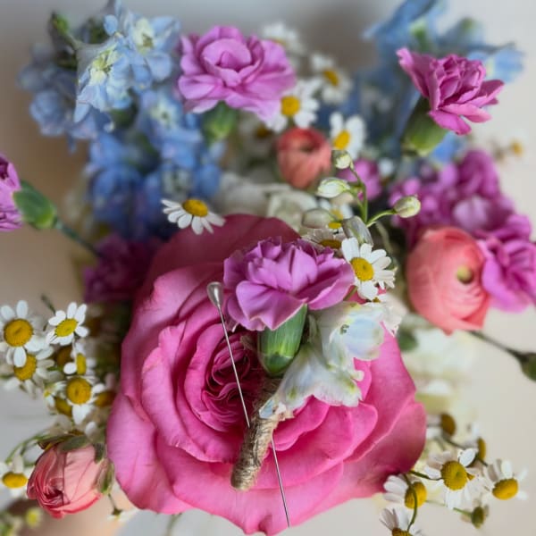 Pink roses with small daisies and blue flowers in a bouquet
