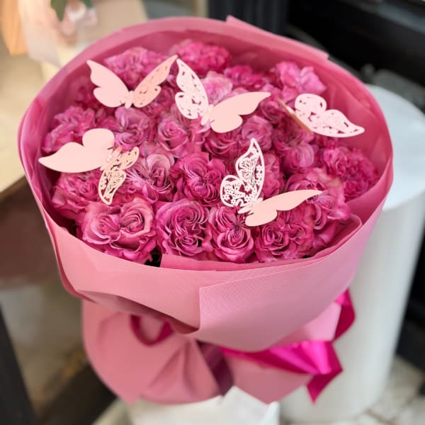 Pink rose bouquet wrapped in pink paper with butterfly decorations