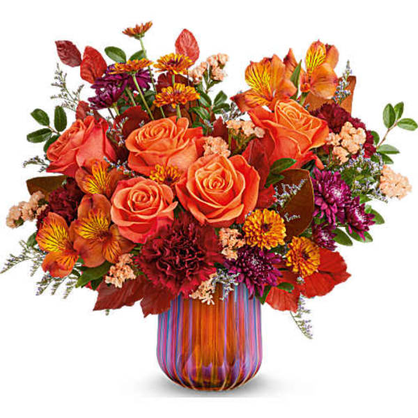 Orange roses and mixed autumn flowers in a striped glass vase