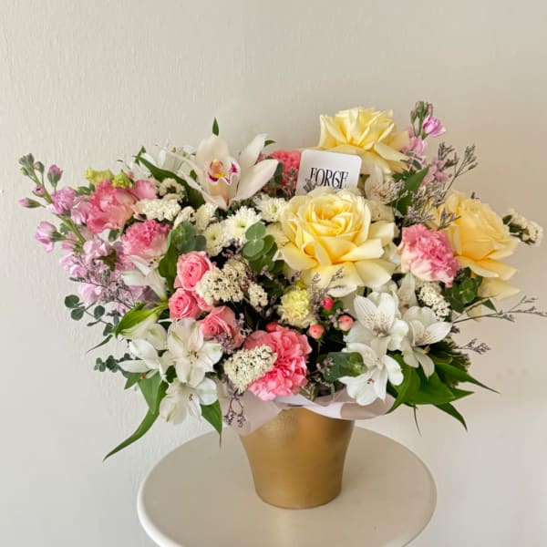 Pink and yellow mixed flower arrangement in a gold vase