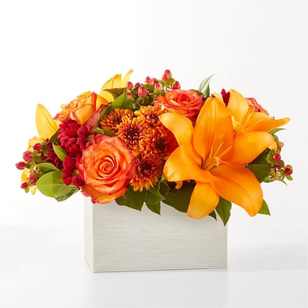 Orange and red flower arrangement in a white box