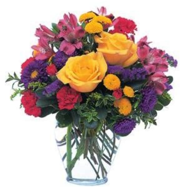 Mixed bouquet of yellow roses, purple and pink flowers in a clear glass vase