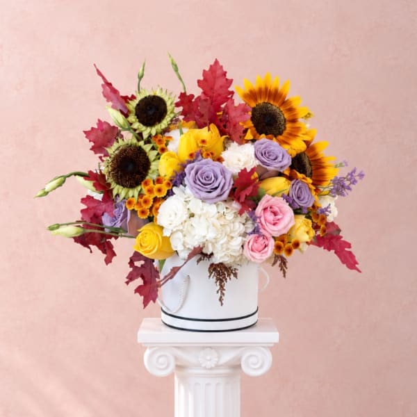 Mixed bouquet with sunflowers, roses, hydrangea, and autumn leaves in a white hatbox