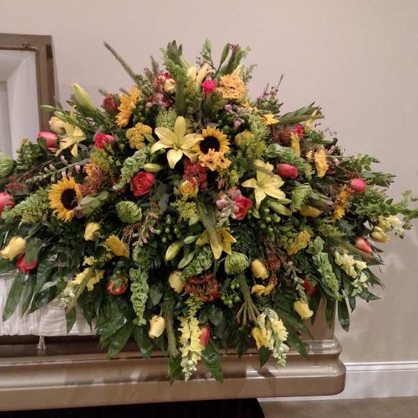 Large mixed floral spray with yellow lilies, sunflowers, and roses