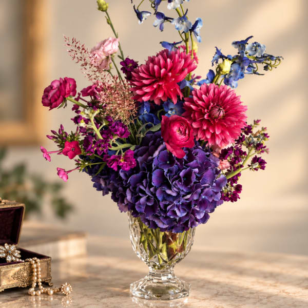 Colorful bouquet of pink, purple, and blue flowers in a clear glass vase