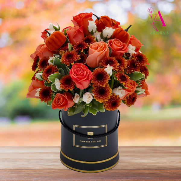 Orange roses and mums arranged in a black hatbox