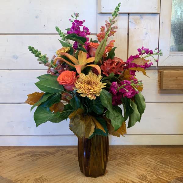 Colorful mixed flower arrangement in a tall brown vase
