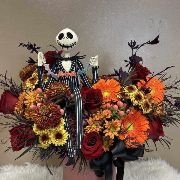 Halloween bouquet with roses, gerbera daisies, and a Jack Skellington figure in a pink box