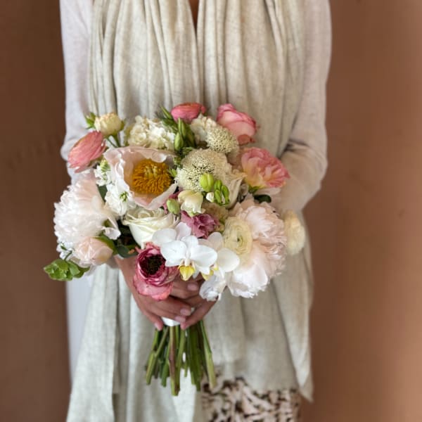 Handheld bouquet of pale pink, white, and cream flowers
