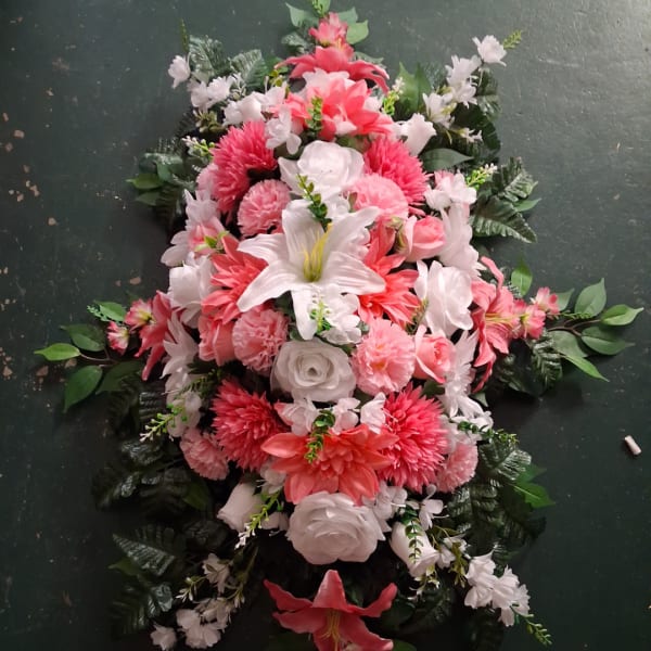Pink and white floral spray with lilies and roses on a dark background