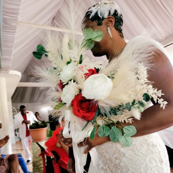 Bride holding a bouquet of red and white roses with white feathers