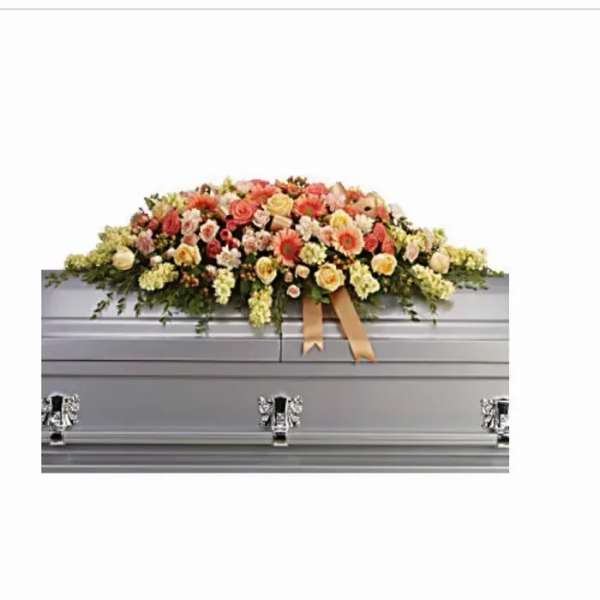 Long pastel casket spray of roses and mixed flowers on a silver casket