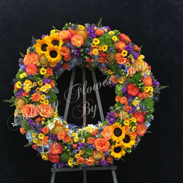 Large circular floral wreath on an easel with sunflowers and roses