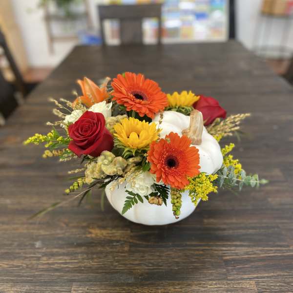 Pumpkin-shaped floral arrangement with orange gerberas, red roses, and yellow blooms