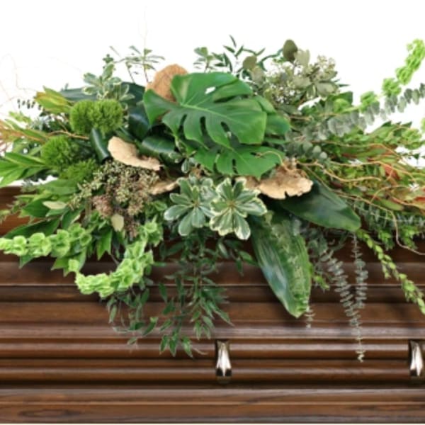 Large green floral spray on a wooden casket