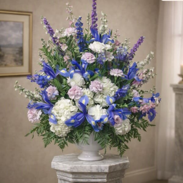 Blue and white floral arrangement in a white pedestal vase