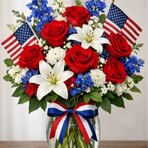 Red roses and white lilies in a glass vase with American flags