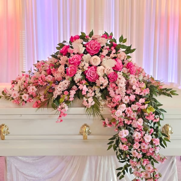 Pink and white floral casket spray with cascading blooms