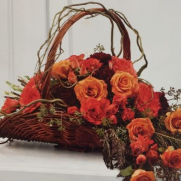 Basket arrangement of orange and red roses with curly branches