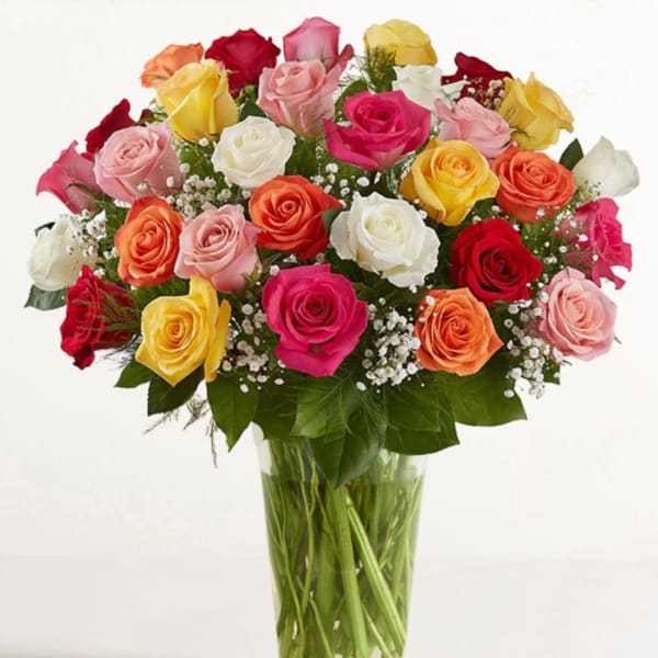 Mixed roses in many colors arranged in a clear glass vase