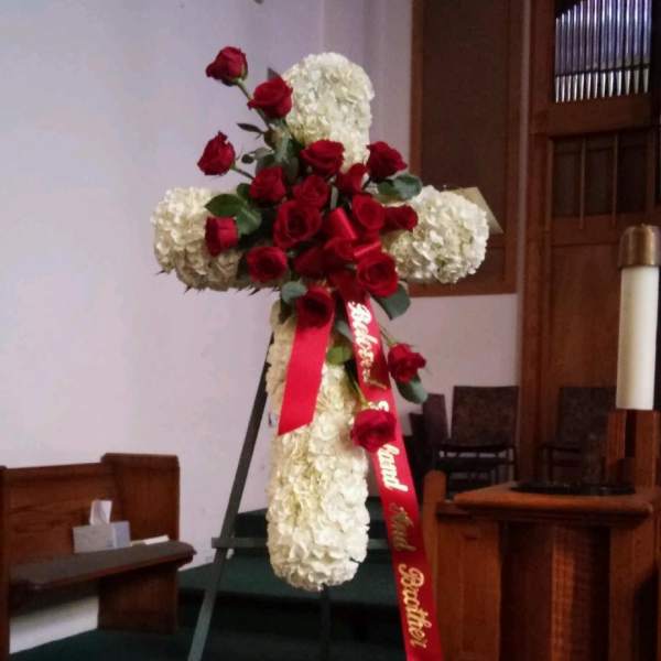 Red roses and white hydrangeas arranged on a standing cross