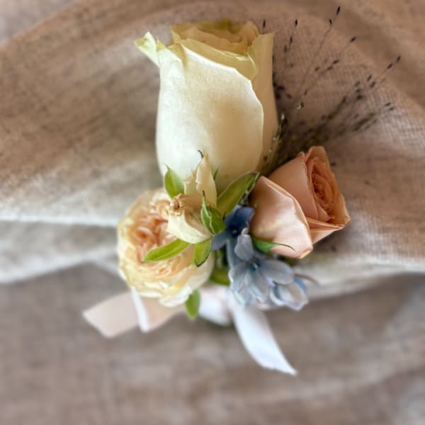 Small bridal bouquet with cream, peach, and blue flowers tied with ribbon