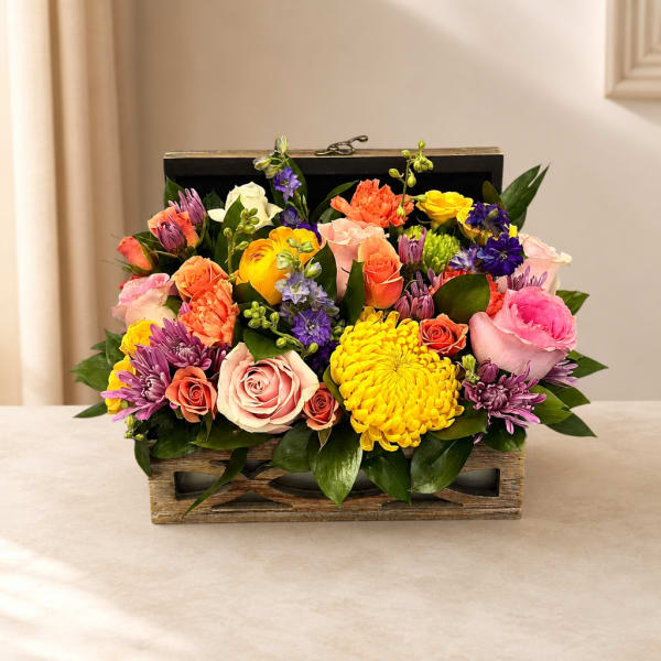 Mixed bouquet of roses, chrysanthemums, and purple blooms in a wooden box