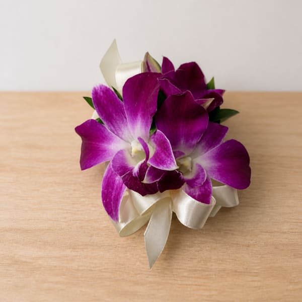 Purple orchid corsage with cream ribbon on a wooden surface