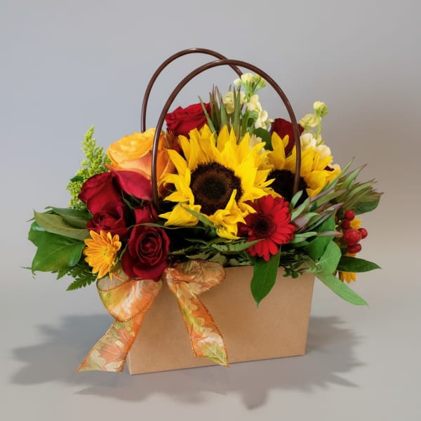 Mixed bouquet with sunflowers, red roses, and a ribboned gift box