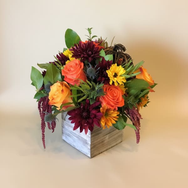 Mixed bouquet of orange and burgundy flowers in a wooden box