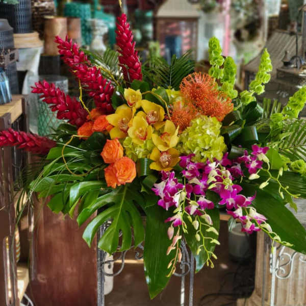 Tropical floral arrangement with orchids, orange roses, and red and green spikes