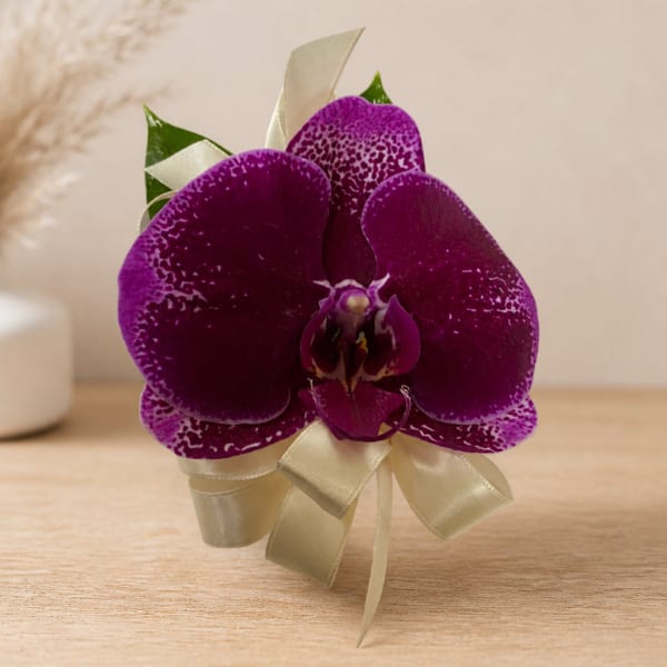 Purple orchid corsage with cream ribbon on a table