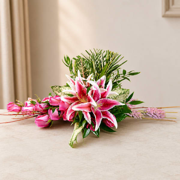 Pink lilies and roses arranged low with greenery