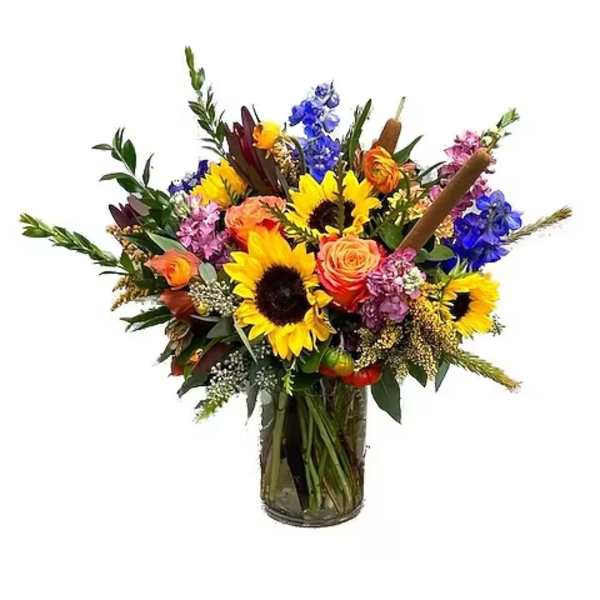 Mixed bouquet with sunflowers, roses, and blue flowers in a glass vase