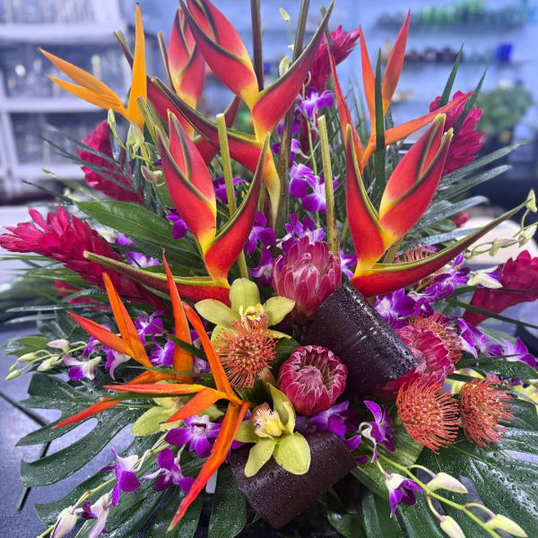 Tropical bouquet with orange heliconia, purple orchids, and pink protea