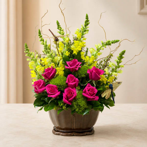 Pink roses and yellow snapdragons arranged in a brown vase