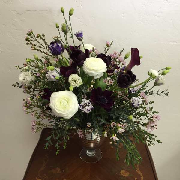 White and dark purple floral arrangement in a glass vase