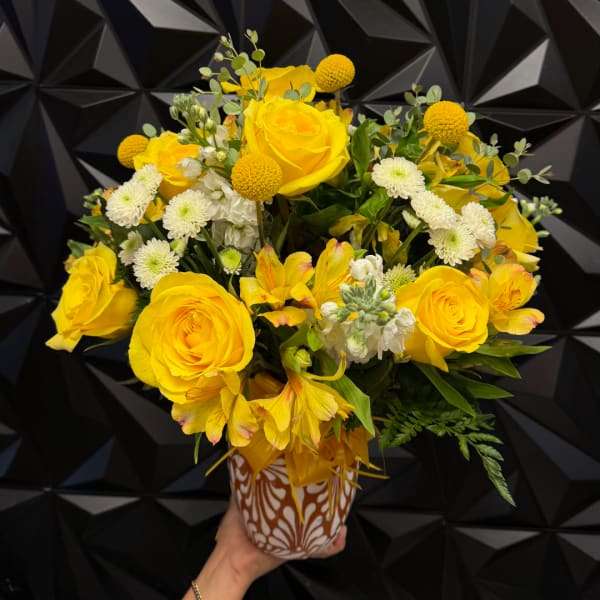 Yellow roses and white mums in a patterned vase