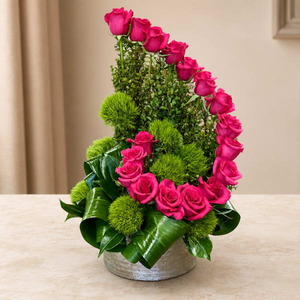 Pink roses arranged in a silver vase with bright green accents.