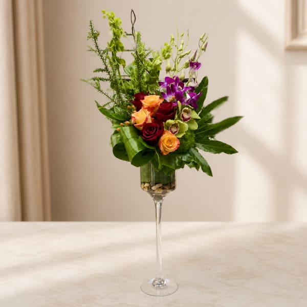Mixed bouquet of roses and orchids in a tall glass vase