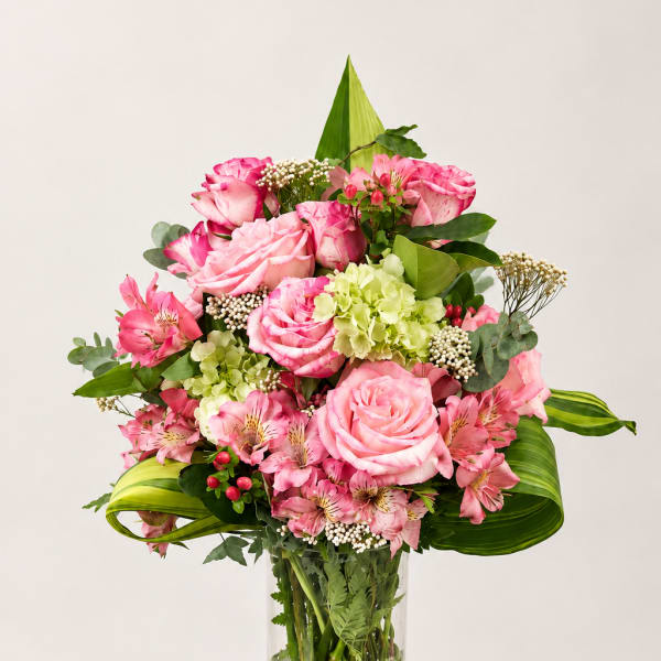 Pink roses and alstroemeria in a glass vase with gold base